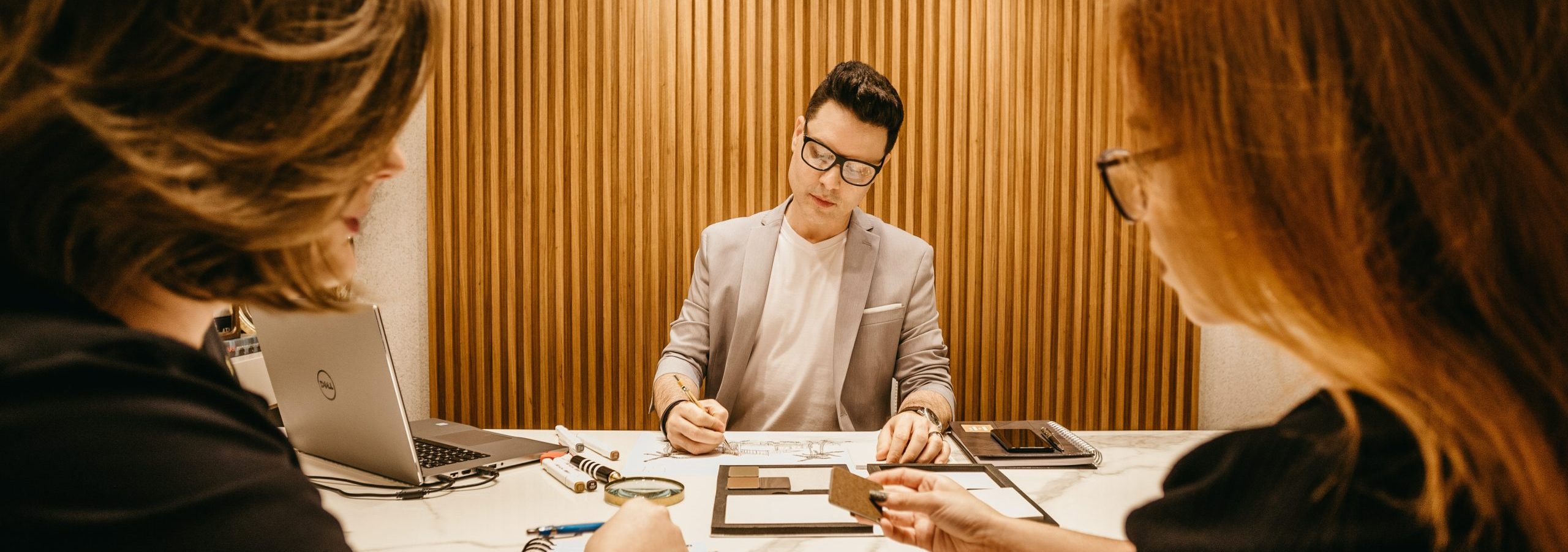 A man in a meeting with two colleagues sits at a table.